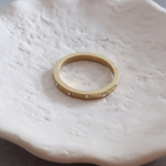 Gold ring on a white ceramic dish with flowers in the background