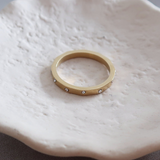 Gold ring on a white ceramic dish with flowers in the background