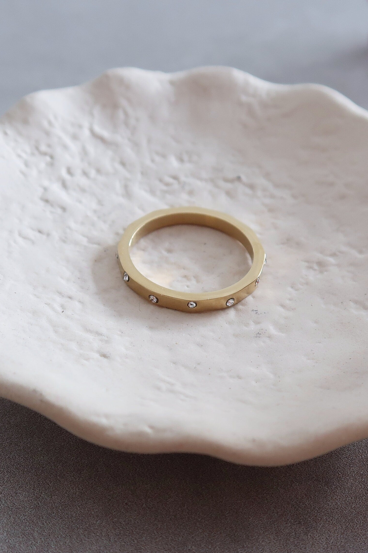 Gold ring on a white ceramic dish with flowers in the background