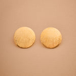 Pair of gold round earrings on a beige background