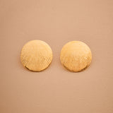 Pair of gold round earrings on a beige background