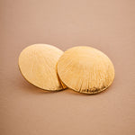 Pair of gold earrings on a beige background