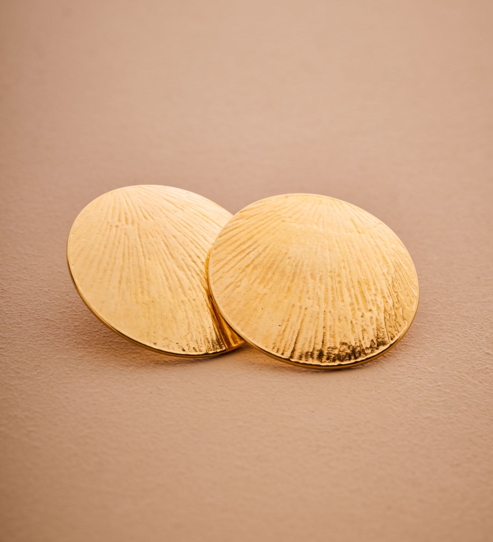 Pair of gold earrings on a beige background