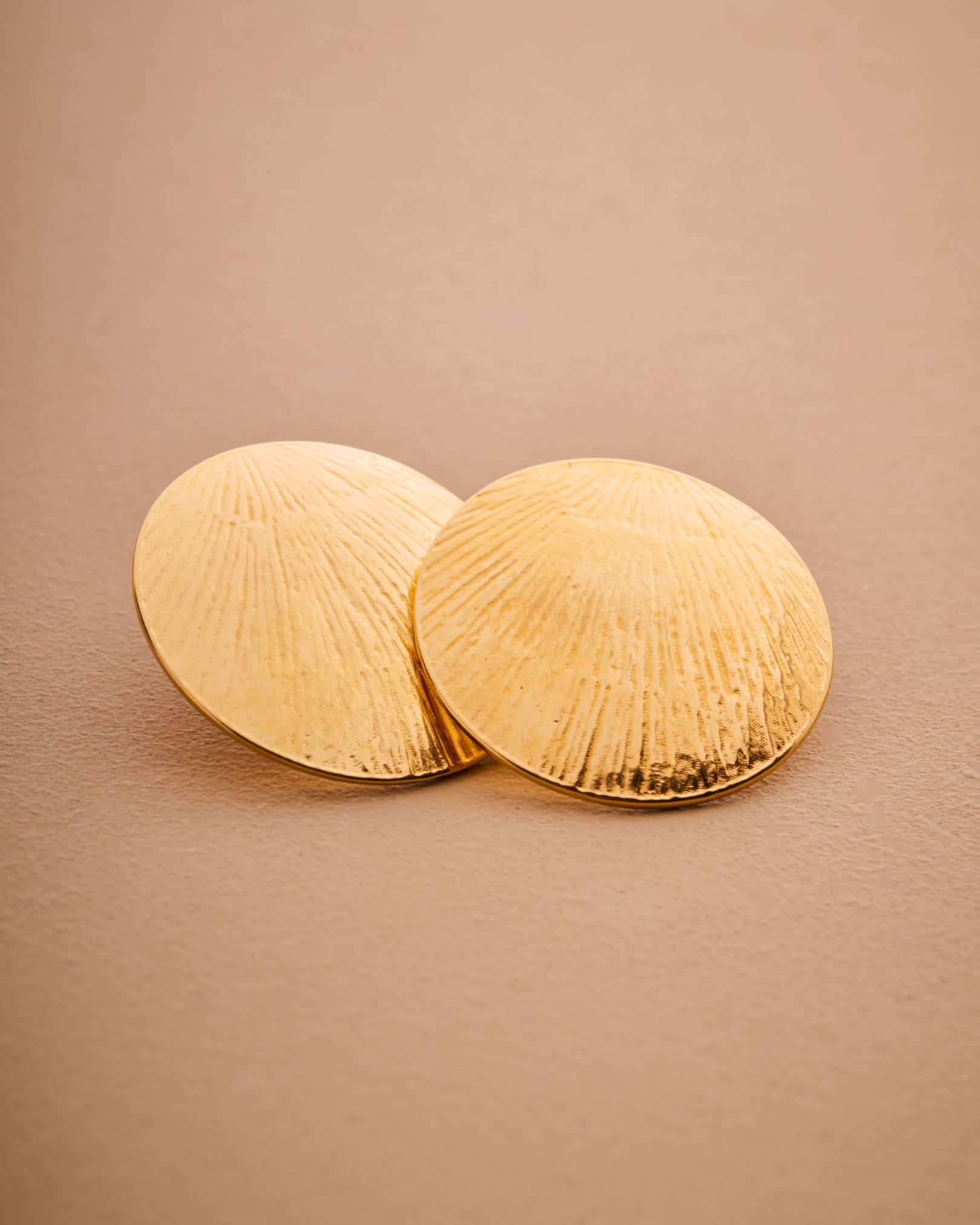 Pair of gold earrings on a beige background