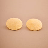 Pair of gold shell-shaped earrings on a beige background